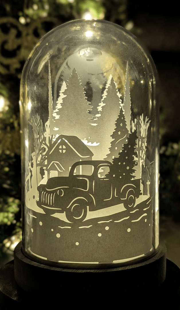 Veilleuse artisanale en papier sous cloche, scène de Noël vintage avec camion et sapin, création lumineuse faite main à Lille.