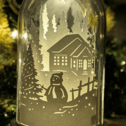Veilleuse artisanale en papier sous cloche, scène d’hiver avec maison enneigée et bonhomme de neige, création lumineuse poétique faite main à Lille.