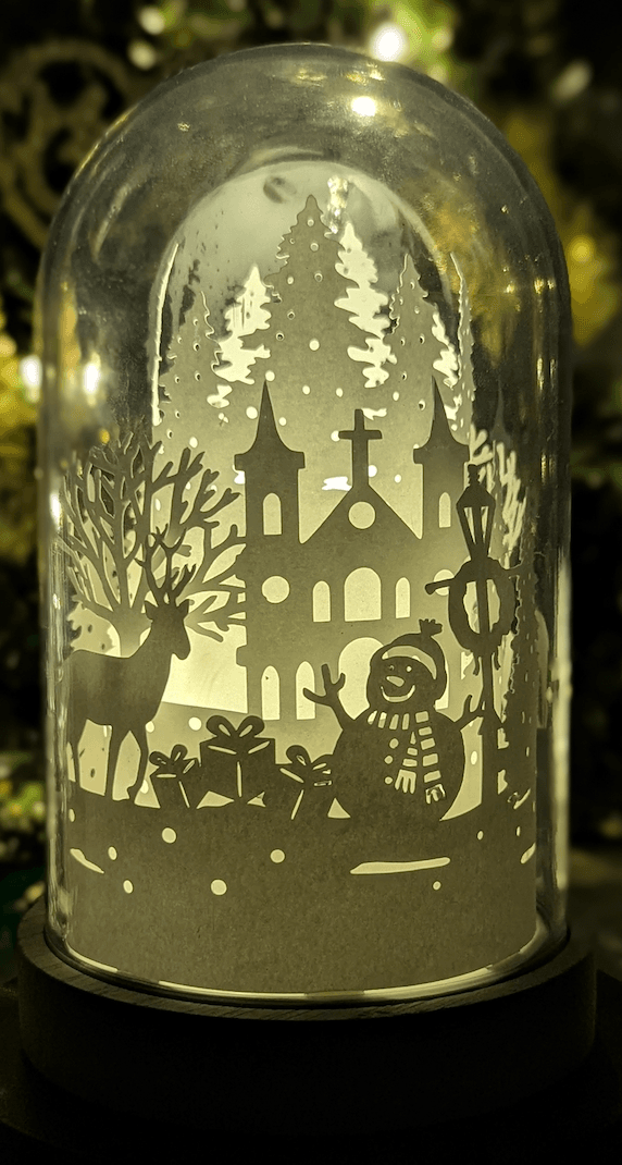 Veilleuse artisanale en papier sous cloche, scène hivernale avec renne et forêt enneigée, création lumineuse poétique faite main à Lille.